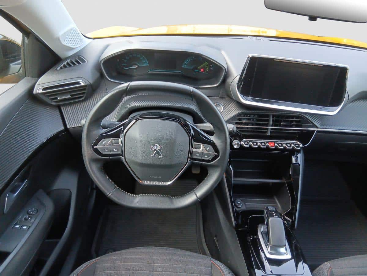 Auf diesem Bild ist das moderne Interieur eines Peugeot-Fahrzeugs zu sehen, inklusive Lenkrad, digitalem Cockpit, Infotainmentsystem und Mittelkonsole.