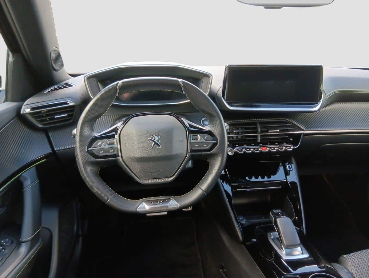 Das Bild zeigt den modernen Innenraum eines Peugeot aus der Fahrerperspektive, inklusive Lenkrad, Armaturenbrett und Infotainment-Display.